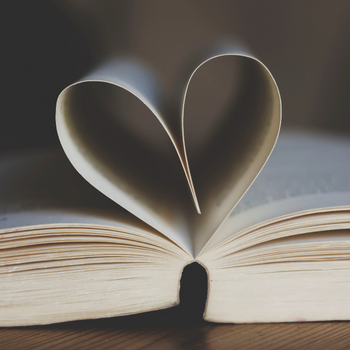 A book lays open on a table, with the middle pages forming a heart.